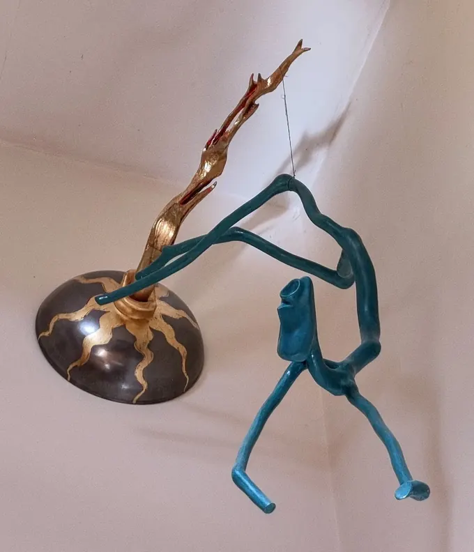 Icarus Unwinged, a carved wood sculpture by Bruce Thomson, a blue-green figure reaching from a domed base towards a gilded wing