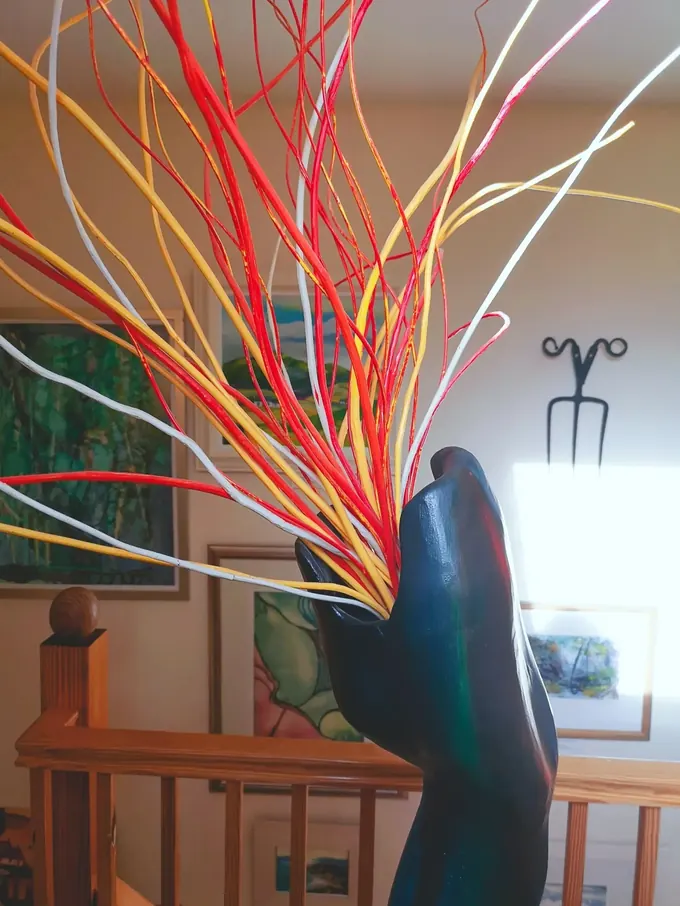 Dragon, a carved wood sculpture by Bruce Thomson, a dark head thrown back with painted red and yellow rods rising from its jaws