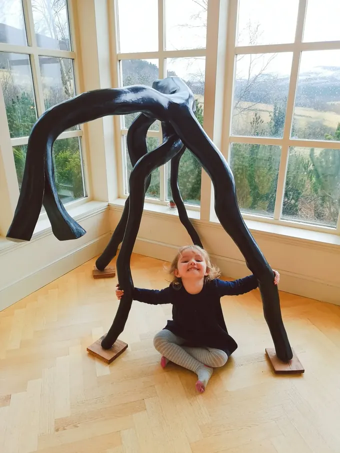 Horse, a large carved wood sculpture by Bruce Thomson, a black form arching over on splayed legs